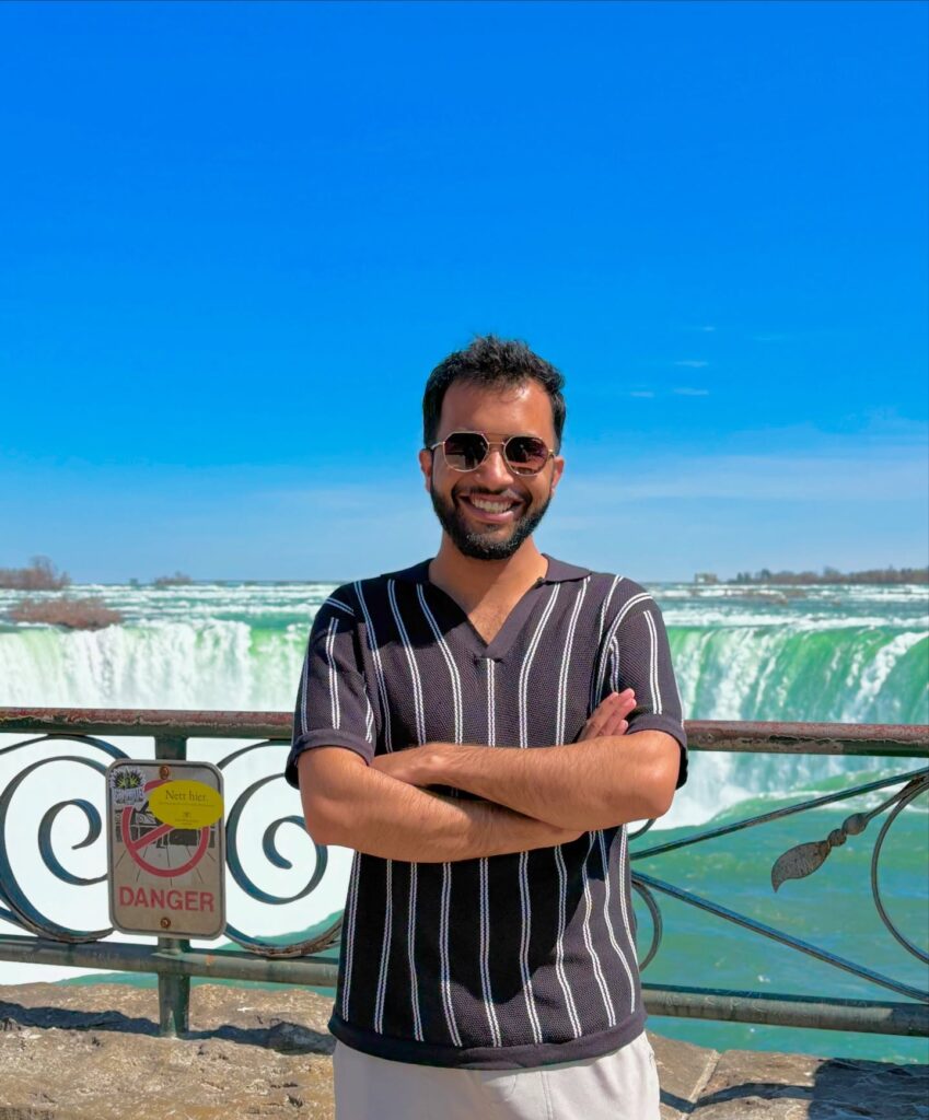 A boy standing front of water fall.